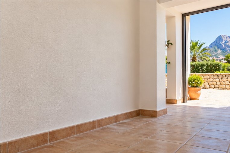 A replastered and repainted wall in a finished room, with a tiled floor and glazed doors open onto a terrace and a mountain view beyond