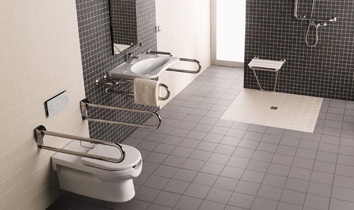An accessible bathroom with grab rails, a wall-hung toilet, a fold-down shower seat and a level-access shower
