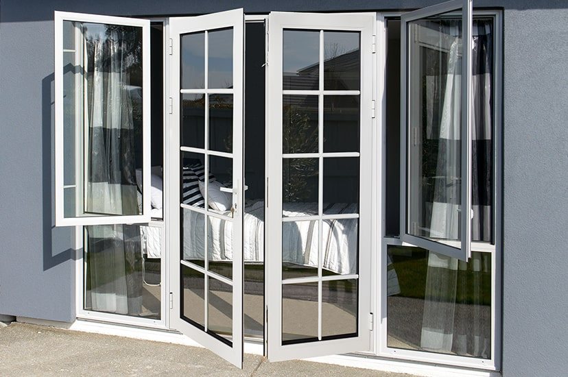 White-framed glazed French doors with glazing bars, open onto a terrace